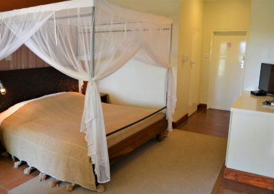 Bed with mosquito net at Africa House in Lilongwe